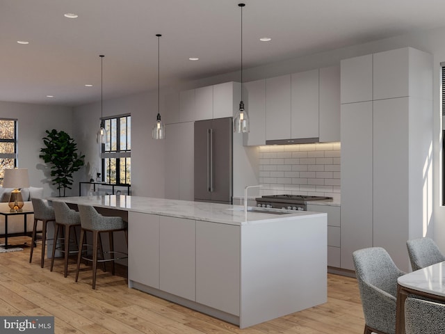 kitchen with appliances with stainless steel finishes, light wood-type flooring, sink, white cabinetry, and a large island