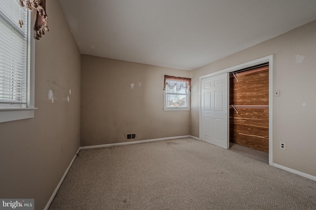 unfurnished bedroom with a closet and light colored carpet