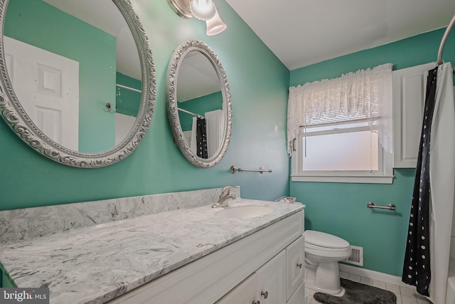 bathroom with toilet, vanity, and tile patterned floors