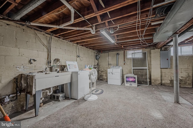 basement featuring electric panel, a healthy amount of sunlight, and independent washer and dryer