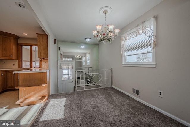 unfurnished dining area featuring carpet and a chandelier