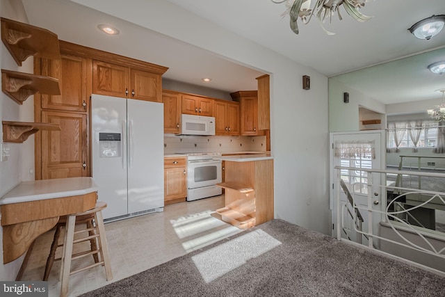 kitchen featuring tasteful backsplash, white appliances, an inviting chandelier, and a kitchen breakfast bar