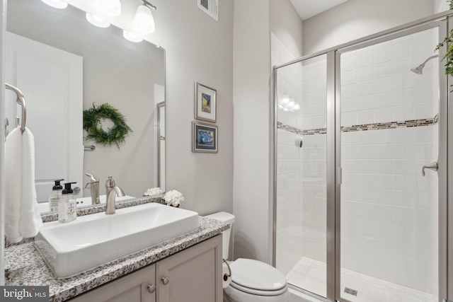 bathroom featuring vanity, toilet, and a shower with shower door