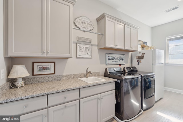 clothes washing area with cabinets, independent washer and dryer, and sink