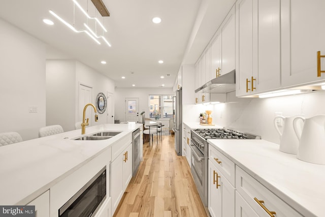 kitchen with white cabinetry, sink, light hardwood / wood-style flooring, and appliances with stainless steel finishes