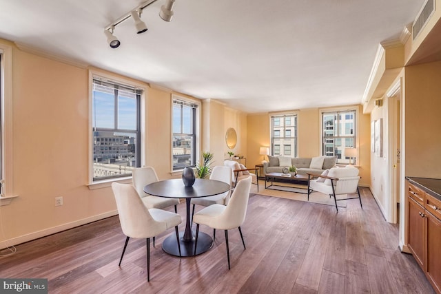 dining space with hardwood / wood-style floors and rail lighting