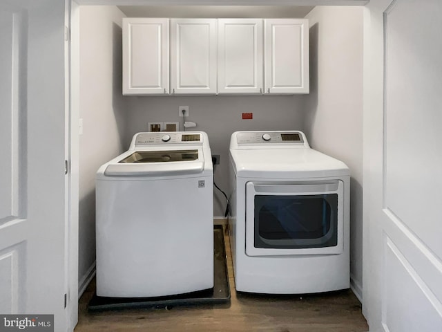 washroom featuring dark hardwood / wood-style flooring, washing machine and dryer, and cabinets