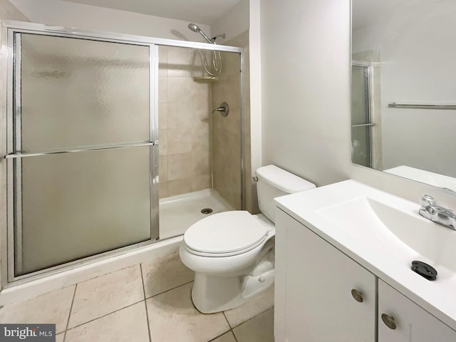 bathroom featuring toilet, an enclosed shower, vanity, and tile patterned floors