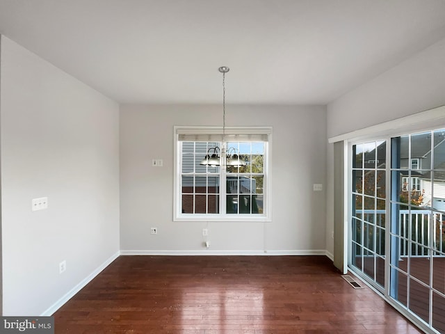 unfurnished dining area featuring dark hardwood / wood-style floors and a chandelier