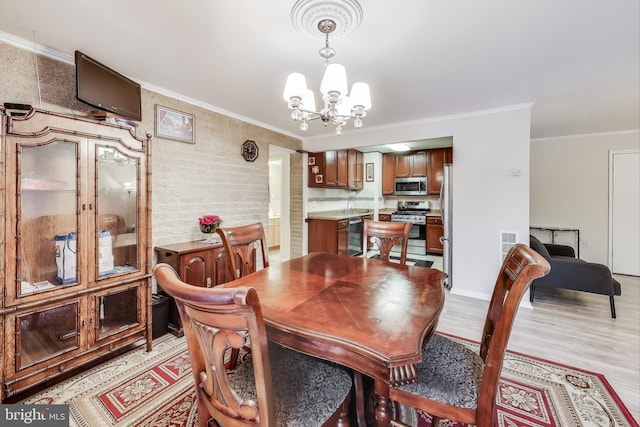 dining space featuring light wood-type flooring, an inviting chandelier, and ornamental molding