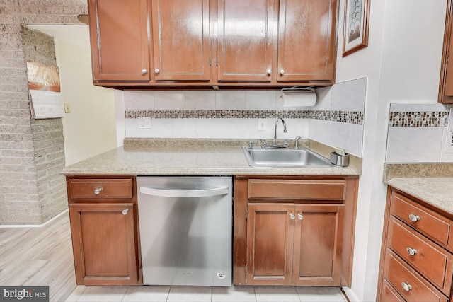 kitchen featuring sink, tasteful backsplash, stainless steel dishwasher, light stone countertops, and light wood-type flooring