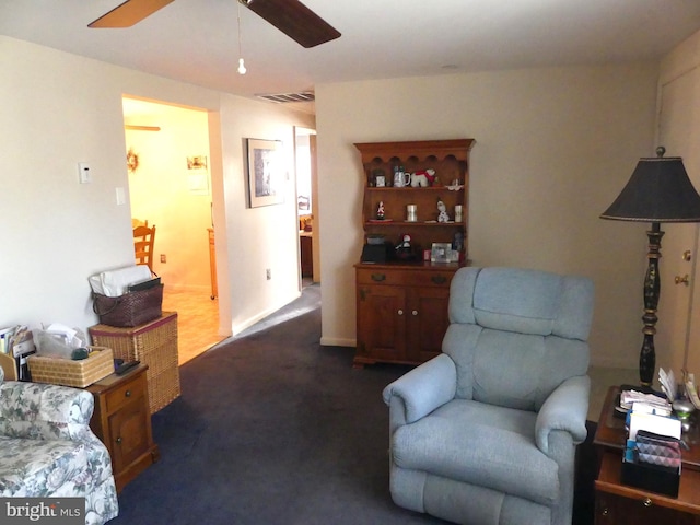 sitting room with ceiling fan and dark carpet