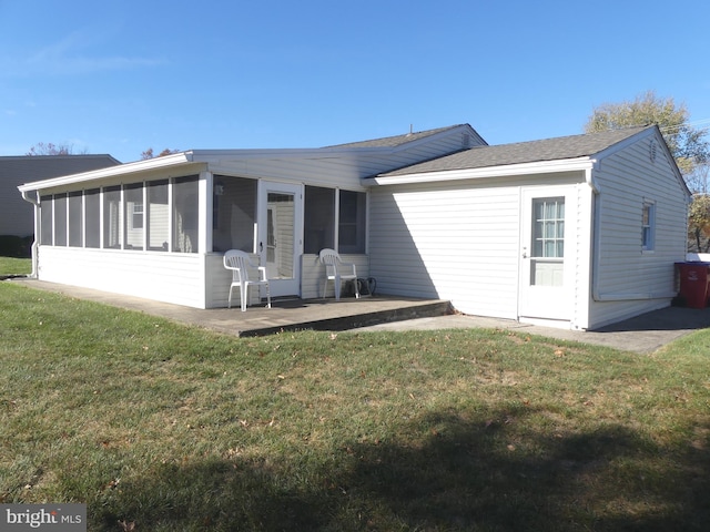 back of property with a lawn, a patio, and a sunroom