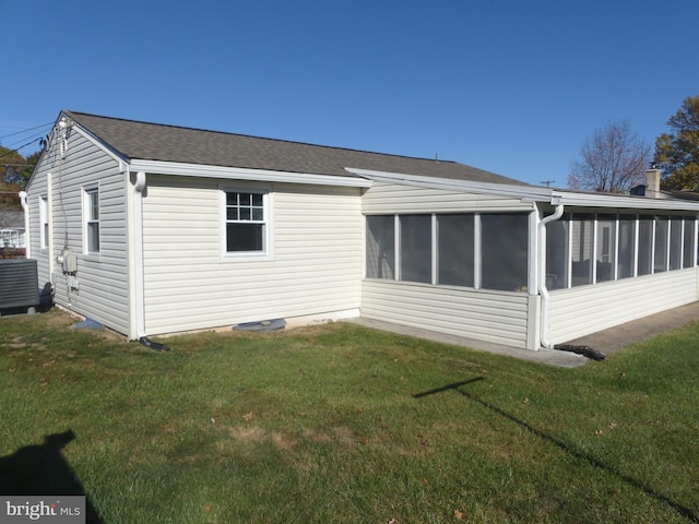 rear view of property with a sunroom, a yard, and central AC