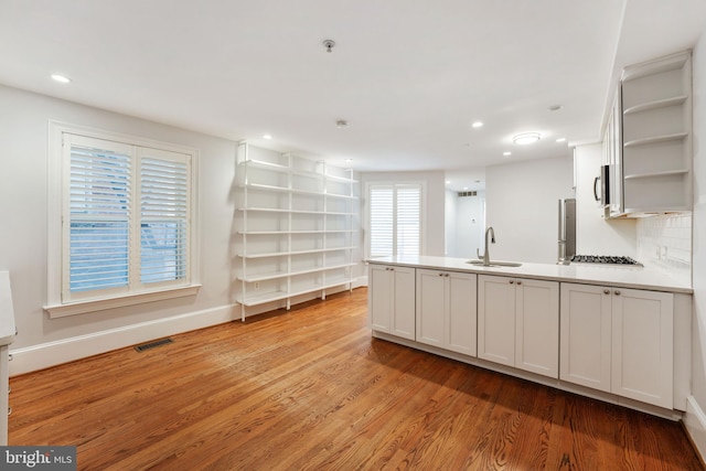 kitchen featuring light hardwood / wood-style flooring, a wealth of natural light, sink, and white cabinets