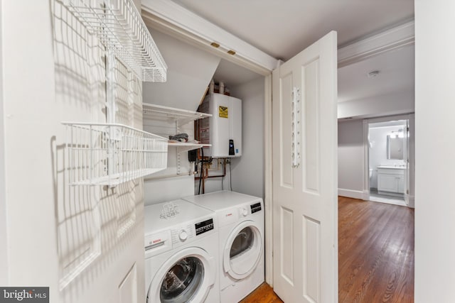 laundry area with hardwood / wood-style floors, washing machine and dryer, and tankless water heater