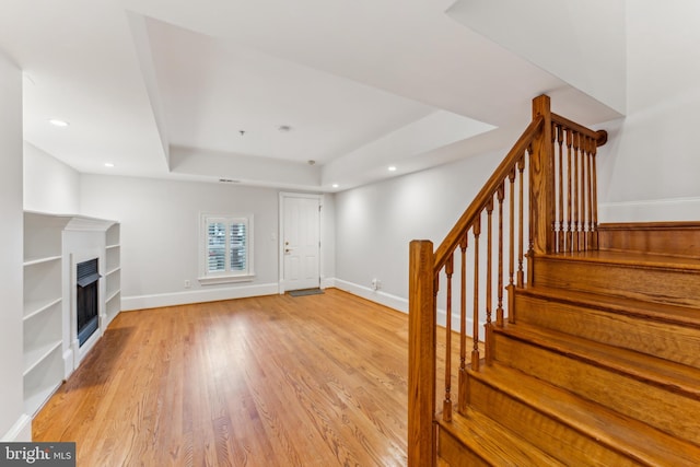 interior space with light wood-type flooring and a tray ceiling