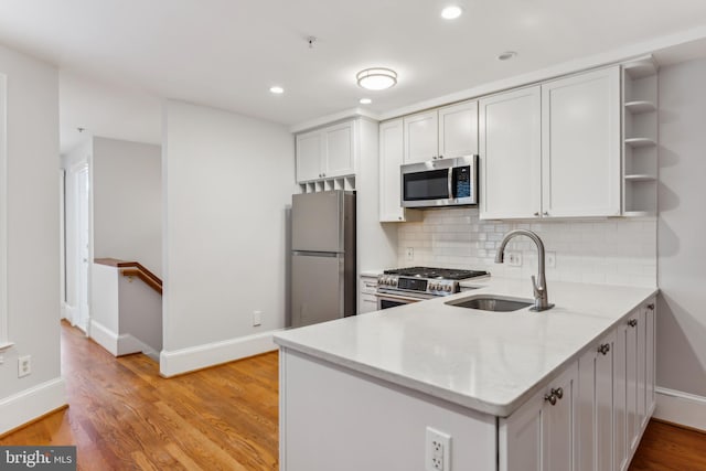 kitchen with stainless steel appliances, white cabinets, and light wood-type flooring