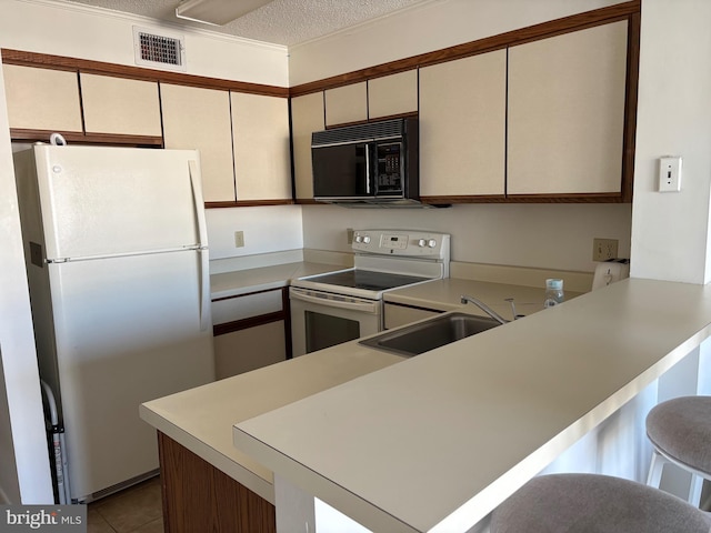 kitchen with white appliances, visible vents, a peninsula, light countertops, and a sink