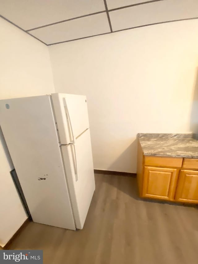 kitchen with hardwood / wood-style flooring, white refrigerator, and a drop ceiling