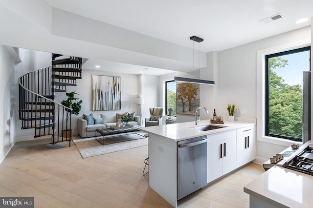 kitchen featuring dishwasher, white cabinets, sink, pendant lighting, and light wood-type flooring