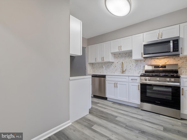 kitchen featuring stainless steel appliances, white cabinets, sink, and light hardwood / wood-style flooring