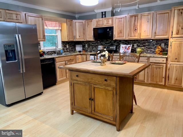 kitchen featuring backsplash, light countertops, crown molding, black appliances, and a sink