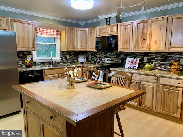 kitchen featuring a sink, ornamental molding, light wood-type flooring, decorative backsplash, and black appliances