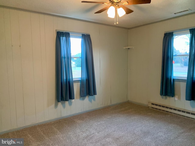 empty room with carpet floors, a baseboard radiator, visible vents, and ceiling fan