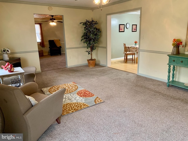 living room featuring ceiling fan, carpet floors, and ornamental molding