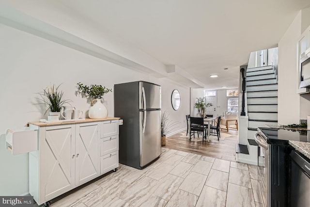 kitchen with light hardwood / wood-style flooring, white cabinetry, light stone countertops, and stainless steel appliances