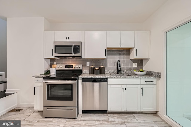 kitchen featuring white cabinets, stainless steel appliances, sink, and light stone countertops