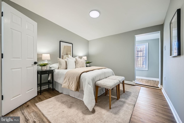 bedroom with lofted ceiling and wood-type flooring