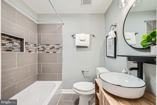 bathroom featuring tile patterned floors, tiled shower / bath, and toilet