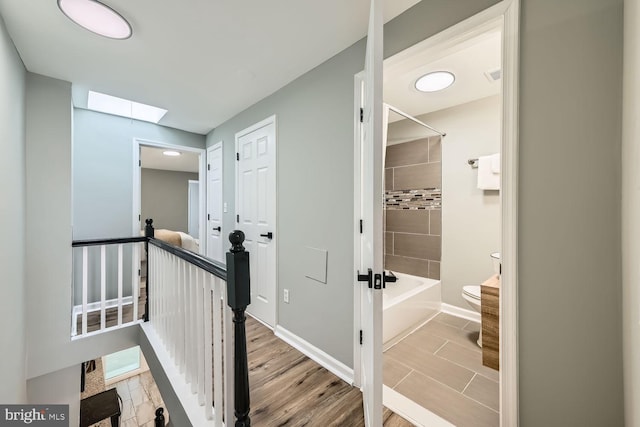 corridor featuring a skylight and wood-type flooring