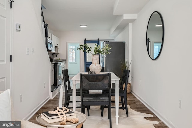 dining area with a barn door and hardwood / wood-style flooring