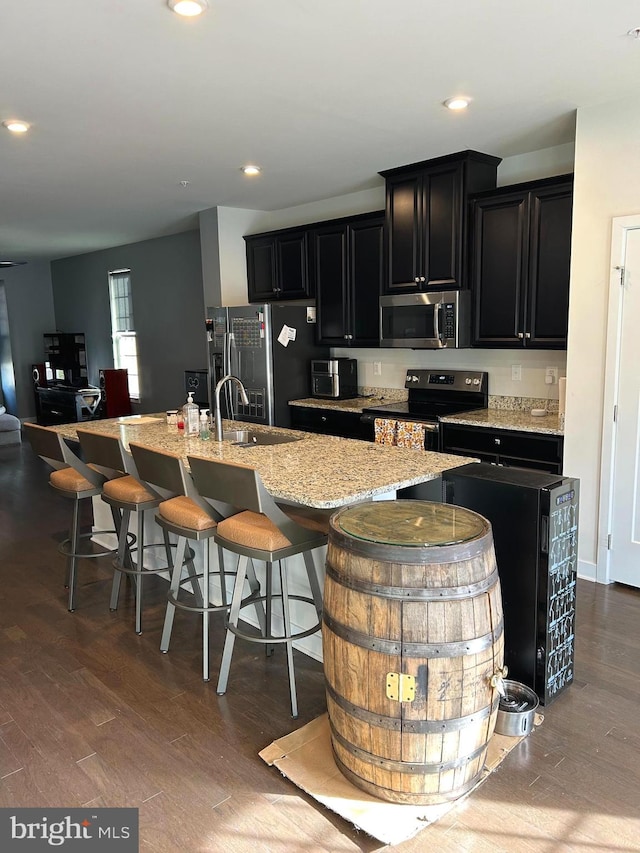 kitchen with a kitchen breakfast bar, sink, an island with sink, dark hardwood / wood-style flooring, and stainless steel appliances