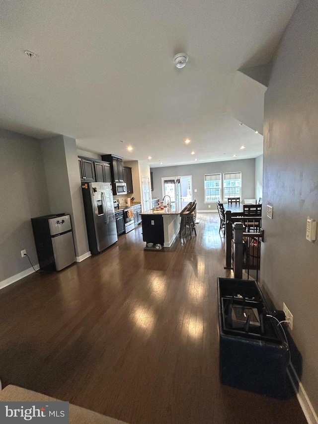 kitchen featuring sink, a breakfast bar area, dark hardwood / wood-style floors, an island with sink, and stainless steel appliances