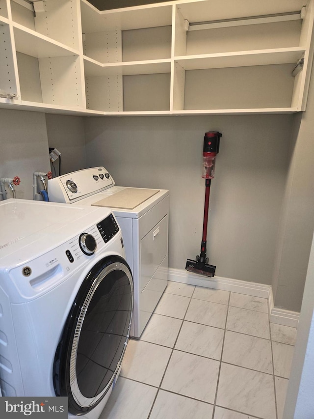 clothes washing area featuring washing machine and dryer and light tile patterned flooring