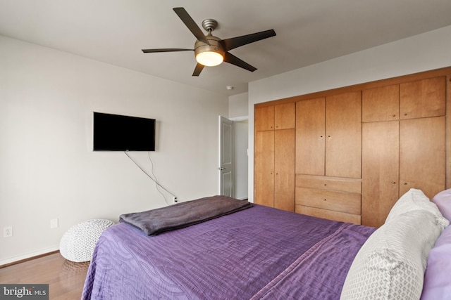 bedroom with a closet, hardwood / wood-style flooring, and ceiling fan