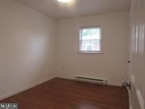 unfurnished room with baseboard heating and dark hardwood / wood-style flooring