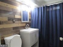 bathroom with walk in shower, sink, and toilet