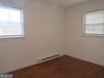 spare room with dark hardwood / wood-style flooring and a baseboard radiator