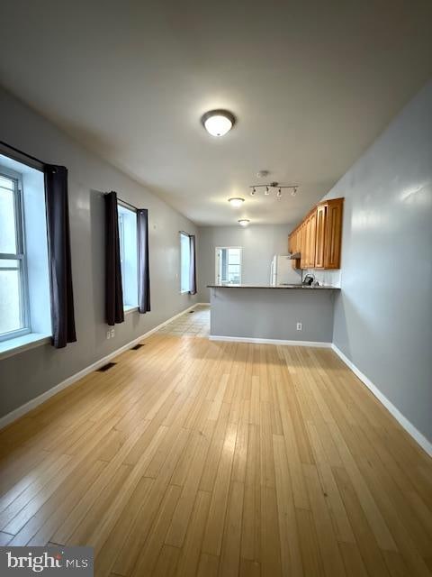 interior space with kitchen peninsula, light hardwood / wood-style flooring, and white fridge