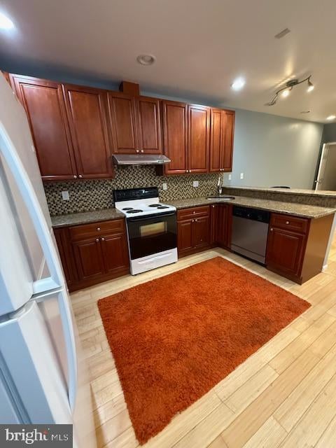 kitchen featuring white appliances, sink, decorative backsplash, light hardwood / wood-style floors, and kitchen peninsula