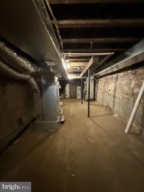 basement with electric water heater, gas water heater, and heating unit