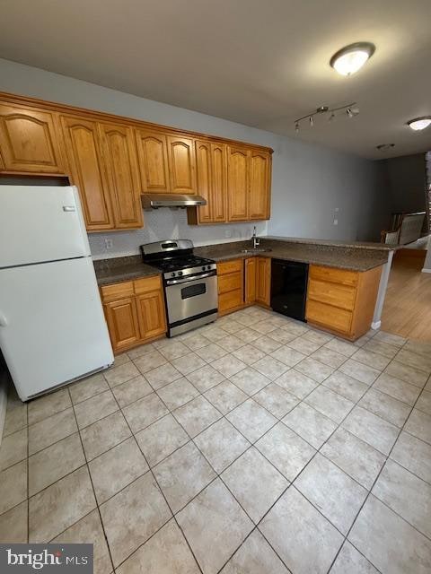 kitchen featuring black dishwasher, gas range, sink, and white fridge