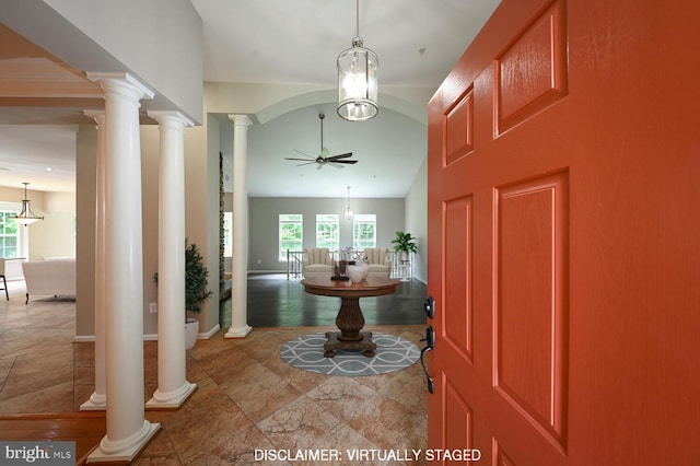 foyer featuring ceiling fan with notable chandelier and decorative columns