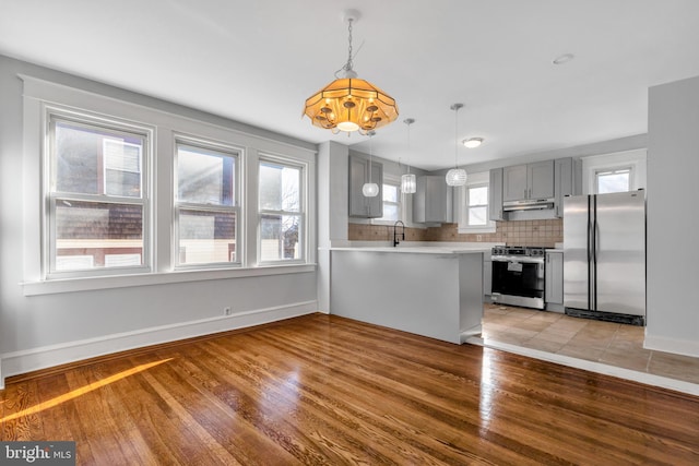 kitchen featuring kitchen peninsula, a healthy amount of sunlight, light wood-type flooring, and stainless steel appliances