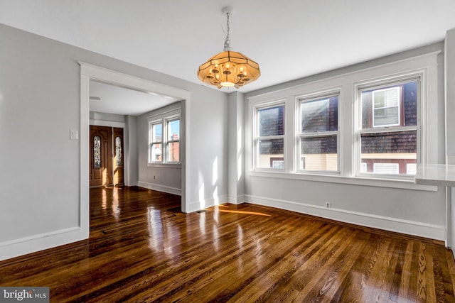 unfurnished dining area with dark hardwood / wood-style flooring and a chandelier